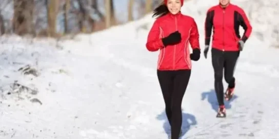 A woman and a man race though snow during the wintertime.